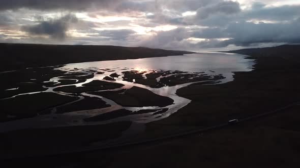 Water with Reflections of Sky and Clouds. Iceland. Lake. River. "White Night". Car drives nearby.