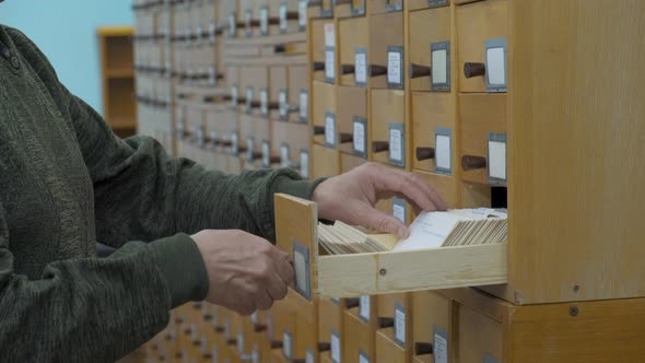 A Male Hand Searching Cards in Old Wooden Card Catalogue