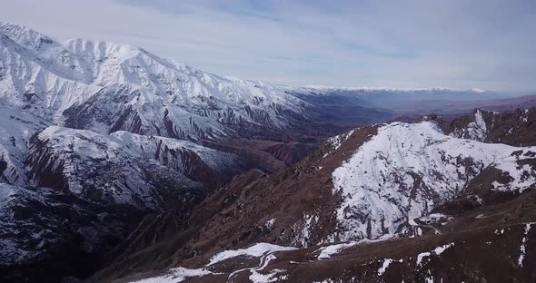 landscape of mountain covered by snow in a wide view cloudy sky visible in horizon. rural road links