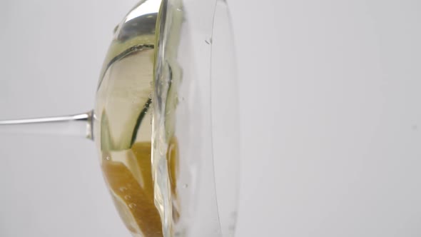 Vertical video, Close-up: lemon fells in a glass of bubbling champagne with cucumber