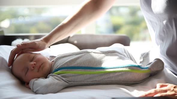 Ginger Woman Mother Gently Patting Her Little Baby Lying on the Baby Cot