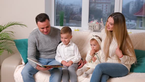 Adorable Family Father Reading a Book to Their Family Sitting in Living Room