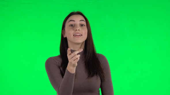 Attractive Girl Listening Attentively and Nods His Head Pointing Finger at Viewer. Green Screen