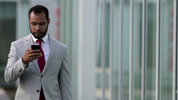 Front View of Focused Businessman Using Smartphone During Stroll