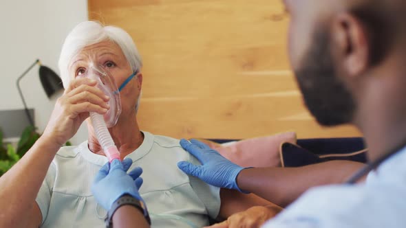 Video of african american male doctor keeping oxygen to caucasian senior woman