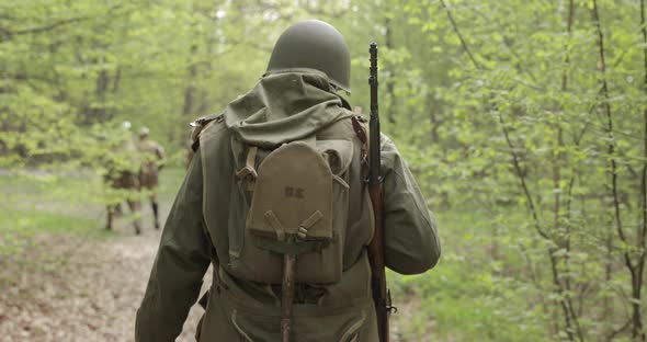 American Soldier Of USA Infantry Of World War II Marching Walking Along Forest Road In Summer Day