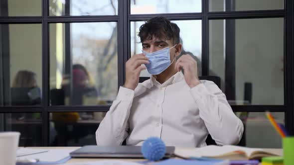 Serious Indian Male in Face Mask Posing in Office