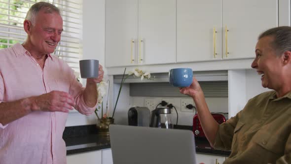 Caucasian senior couple drinking coffee together in the kitchen at home