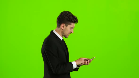 Guy Looks at the Photo on the Phone and Finds a List of Pictures,. Green Screen. Side View