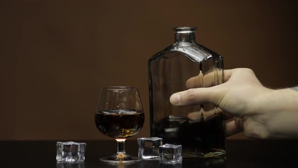 Pouring Whiskey, Cognac Into Glass. Dark Background. Pour of Alcohol Drink