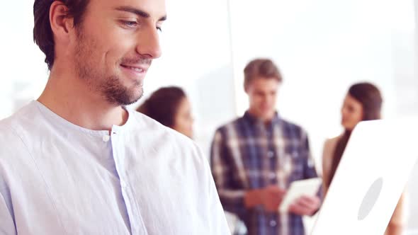 Executive using laptop while colleague discussing in background