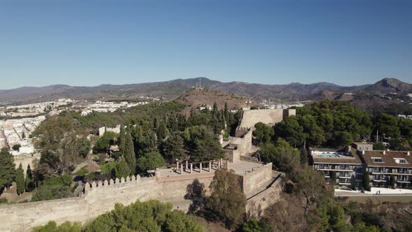 Gibralfaro Castle on greenery hilltop on Malaga city, Spain. Andalusia. Aerial orbiting