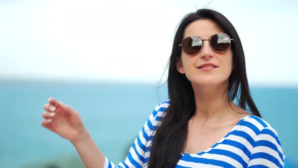 Medium Closeup of Fashionable Touristic Woman Wearing Sunglasses at Sea Sky Natural Background