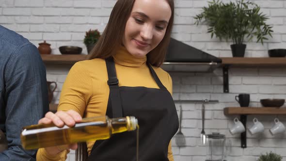 Cooking Salad at Home Attractive Young Woman Pouring Olive Oil on Fresh Salad