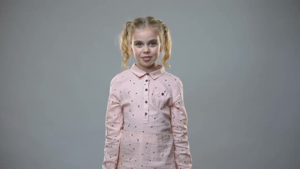 Smiling Little Girl Holding Colorful Purchase Bags on Grey Background, Presents