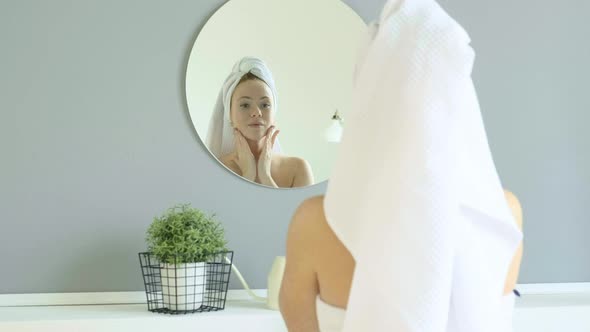 Woman standing in  bathroom, takes from jar and applies face