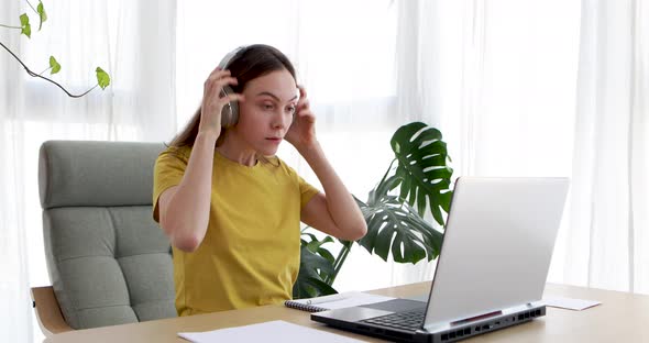 Woman Putting on Headphones While Sitting in Front of a Laptop