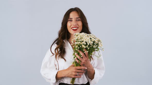 Lady in White Shirt is Catching Bouquet of Chamomile Flowers Sniffing It and Enjoying Smell While