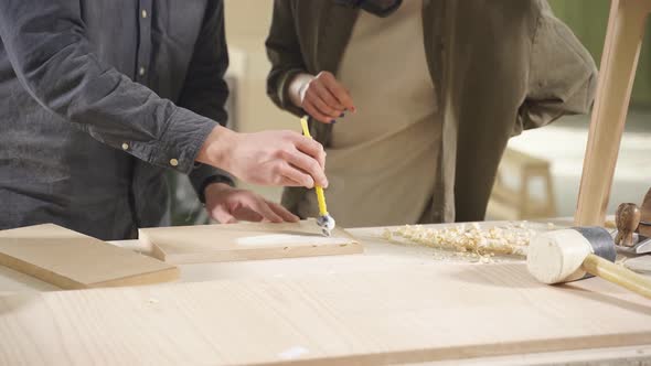 Carpenter Paints Wooden Slat for Production of Furniture on Table in Workshop