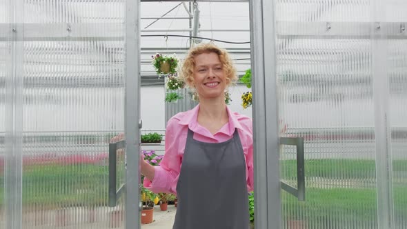 Happy Blonde Florist Gardener Enjoys Working in Her Greenhouse Walking Through Flower Saplings