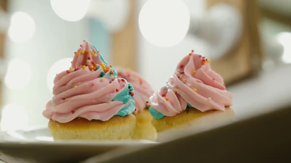 Muffins with Bright Cheese Cream or Cream with Caramel Chips Closeup on the Background of Lights Out