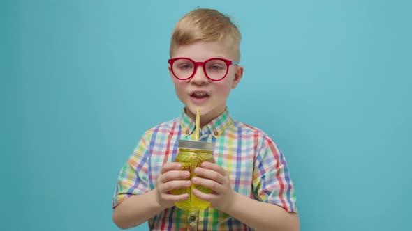 Preschool Boy in Eyeglasses Drinking Water with Straw Holding Bottle on Hands Smiling Looking at