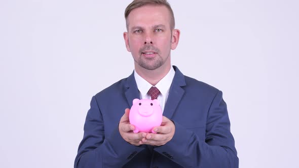 Happy Blonde Businessman Holding Piggy Bank