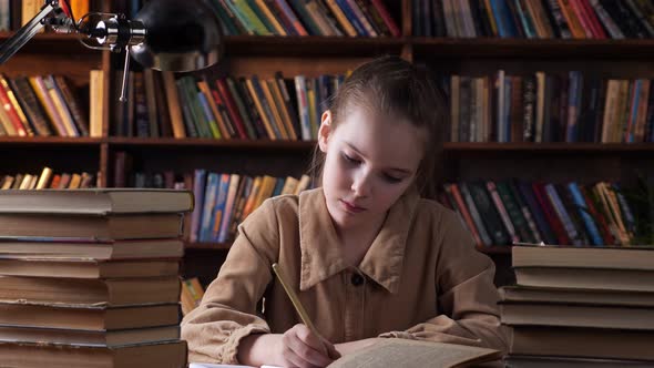 Bored Schoolgirl Looks Into Book and Writes in Copybook