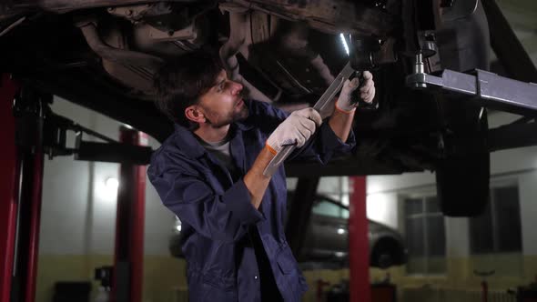 Repairman Working with Mount Under Car Bottom