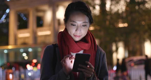 Woman use of mobile phone and hold shopping bag in city at night