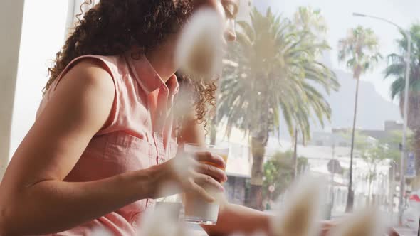 Happy biracial woman spending time at cafe, drinking coffee and using laptop