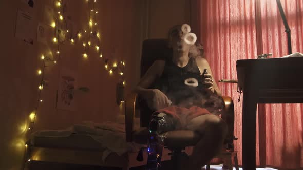 Man with Leg Prosthesis Blows Smoke Rings in Semidark Room