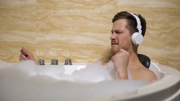 Active Man in Headphones Taking Bath With Foam and Moving to Rhythm of Music