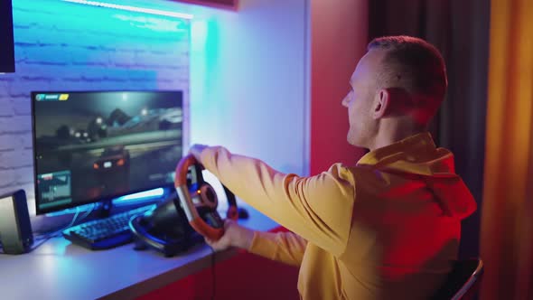 Young gamer driving the steering wheel of a racing simulator. 