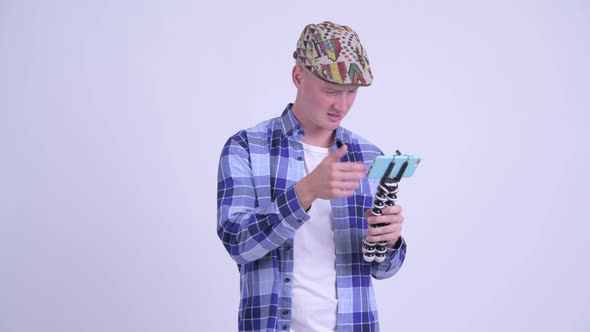 Stressed Young Hipster Man As Vlogger Fixing Phone on Tripod