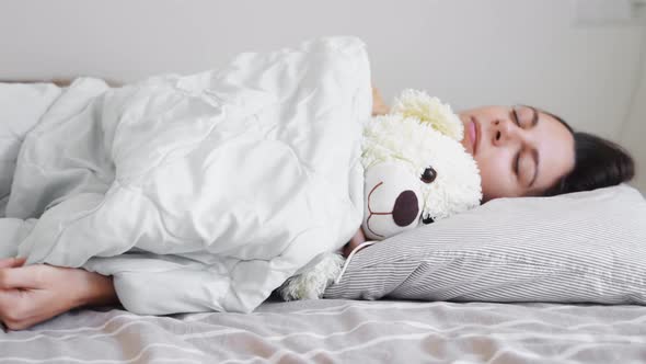 Young Woman Goes to Sleep with Teddy Bear in Her Bedroom