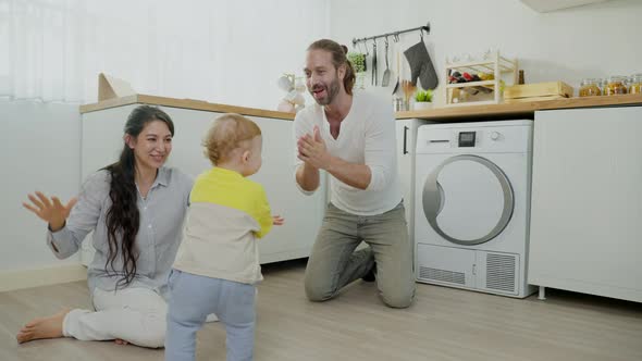 Caucasian baby boy child learn to walk with parents support feel glad and happiness in house.