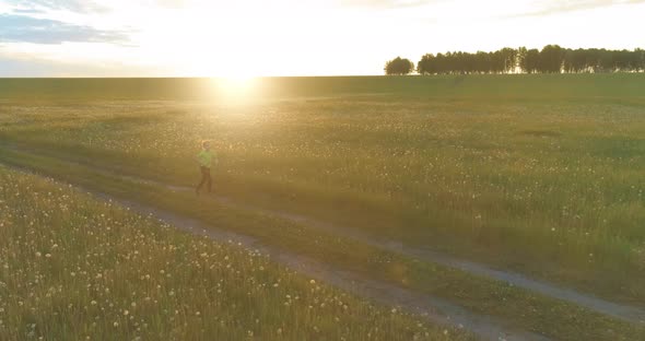 Sporty Child Runs Through a Green Wheat Field. Evening Sport Training Exercises at Rural Meadow. A