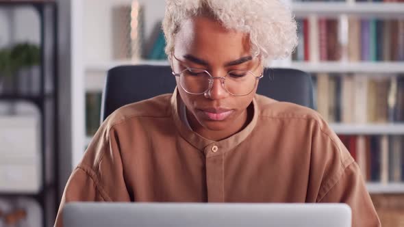 Young African American Woman Hesitant Typing and Looking at Laptop