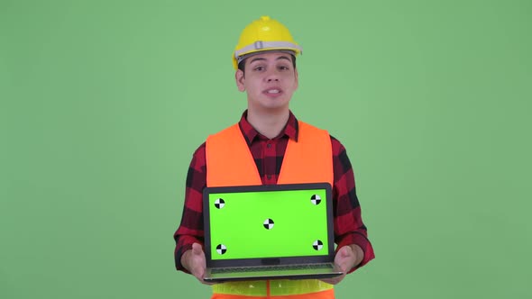 Happy Young Multi Ethnic Man Construction Worker Talking While Showing Laptop