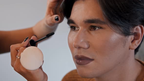 Make Up Artist Doing a Brown Bold Lips with Nude Eyes Look on Her Male Model - Applying Mascara on