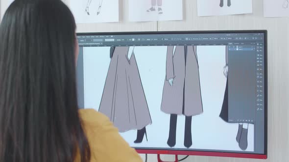 Over The Shoulder View Of A Female Designer Designing Clothes On A Desktop In The Studio