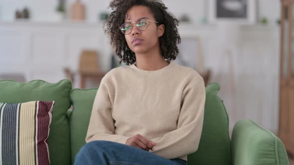 Serious Young African Woman Sitting on Sofa