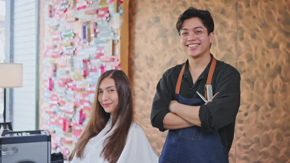 Asian hairdresser's feel happy of his service on customer's hair making arm crossed, look at camera.