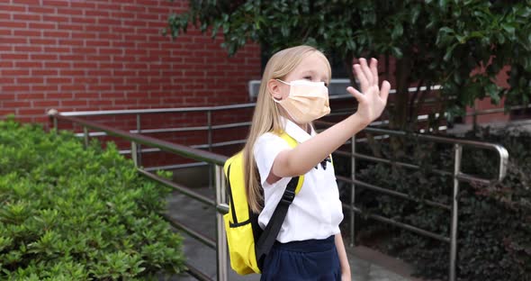 Happy Little Caucasian Blonde Girl Seven Years Old in Uniform with Yellow Backpack Standing Near
