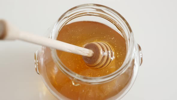 Putting  honey dipper  in honey jar close-up 4K 2160p 30fps UltraHD footage - Sticky sweet food subs