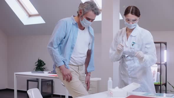 Girl Vaccinates a Man Against Coronavirus in a Bright Private Clinic