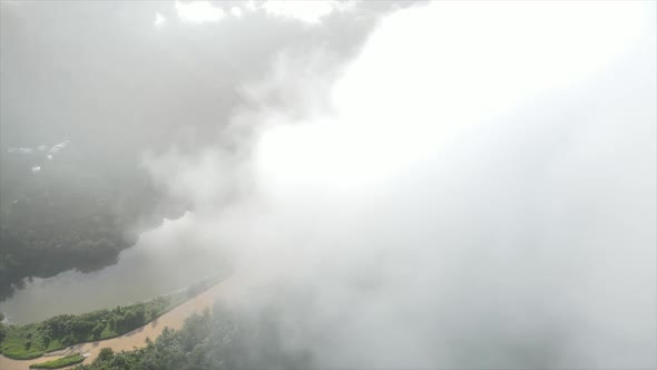 Thick clouds over river in hilly forested valley