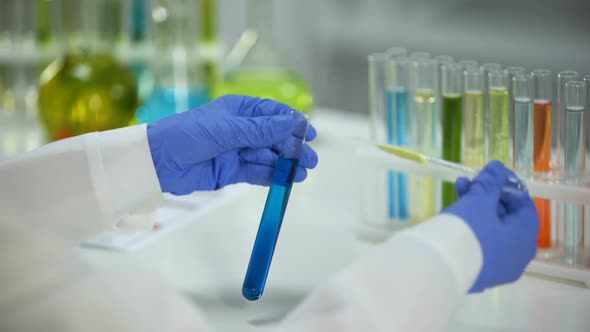 Lab Assistant Dripping Yellow Liquid in Tube With Blue Chemical Substance, Test