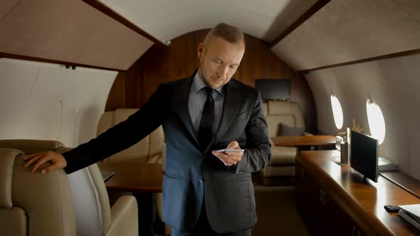 Portrait of Entrepreneur with Phone Inside of Expensive Business Jet.
